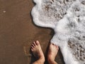 Male feet barefoot stand on the sandy beach with wave motion coming to the foot. Royalty Free Stock Photo