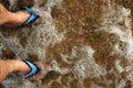 male feet in beach slippers ankle-deep in transparent sea water Royalty Free Stock Photo