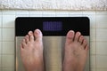 Male feet on digital bathroom weight scale with blank display