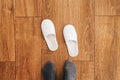 Male feet and disposable white slippers in hotel room