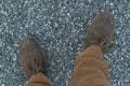 Male feet in leather brown shoes and mustard trousers