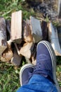 Male feet in sneakers. The wood for the grill is visible. Close-up shot Royalty Free Stock Photo