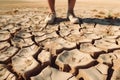 Male feet standing on parched landscape. Drought, disaster and crop failure.