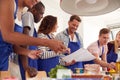 Male And Female Adult Students Looking At Recipe In Cookery Class In Kitchen