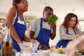 Male And Female Adult Students Smelling Ingredients In Cookery Class