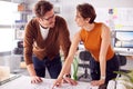 Male And Female Architects Standing In Office Looking At Plan Or Blueprint On Desk Royalty Free Stock Photo