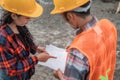 Male and female asian contractors wearing safety helmets holding the site plan building Royalty Free Stock Photo