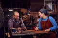 Male And Female Blacksmith Working On Design In Forge Together