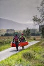 Man and woman carry two canoes along single track road, Glencoe, Scotland. Royalty Free Stock Photo