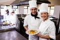 Male and female chefs holding plate of prepared pasta in kitchen Royalty Free Stock Photo