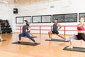 Clients Performing Yoga On Mat In Gym