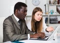 Male and female colleagues working with laptop and documents at table Royalty Free Stock Photo