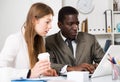 Male and female colleagues working with laptop and documents at table Royalty Free Stock Photo