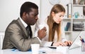 Male and female colleagues working with laptop and documents at table Royalty Free Stock Photo