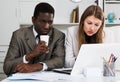 Male and female colleagues working with laptop and documents at table Royalty Free Stock Photo