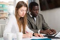 Male and female colleagues working with laptop and documents at table Royalty Free Stock Photo