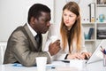 Male and female colleagues working with laptop and documents at table Royalty Free Stock Photo