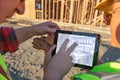 Male and Female Construction Workers Reviewing Kitchen Drawing on Computer Pad at Construction Site. Royalty Free Stock Photo
