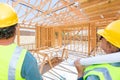 Male and Female Contractors Overlooking New House Framing At Construction Site