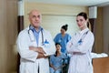 Male and female Doctors wear coats uniform crossed arm standing at patient room in hospital. Team doctors treatment Royalty Free Stock Photo