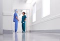 Male And Female Doctors Wearing Scrubs Meeting In Busy Hospital Corridor Royalty Free Stock Photo