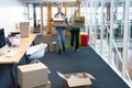 Male and female executives carrying cardboard boxes in office Royalty Free Stock Photo