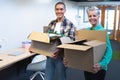 Male and female executives carrying cardboard boxes in office Royalty Free Stock Photo