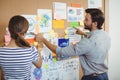 Male and female executives discussing over bulletin board Royalty Free Stock Photo