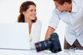 Male and female executives using laptop. Male and female executives using laptop and looking at each other with camera Royalty Free Stock Photo