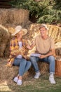 Male and female farmers sitting on hay with bunch of millet spikelets Royalty Free Stock Photo