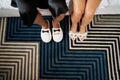 Male and female feet in slippers stand on a carpet. Caption: Groom. Bride. Cropped, faceless Royalty Free Stock Photo