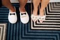 Male and female feet in slippers stand on a striped carpet. Caption: Groom. Bride. Cropped, faceless Royalty Free Stock Photo