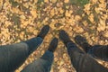 Male and female feet are standing on the yellow autumn leaves. Women`s legs. A young couple in boots is standing in the woods. Royalty Free Stock Photo