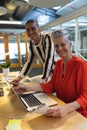 Male and female graphic designers discussing over photographs at desk in office Royalty Free Stock Photo