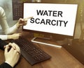 Male and female hand, computer with text Water scarcity with office background