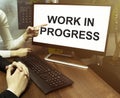 Male and female hand, computer with text Work In Progress with office background Royalty Free Stock Photo