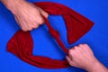 Male and female hand pulling a red scarf with a knot on a blue background