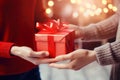 Male and female hands celebrate New Year with a red gift box