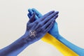 Male and female hands colored in flags of Ukraine and NATO