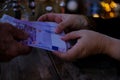 male, female hands with euro banknotes, money close-up, session of magic in dark room of fortuneteller, magic items on table,