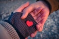 Male and female hands hold a small red heart in the sunset light. Royalty Free Stock Photo