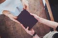 Male and female hands holding a book in a black cover. Royalty Free Stock Photo