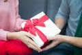 Male and female hands holding gift golden box with red ribbon. Present for birthday, valentine day, Christmas, New Year. Royalty Free Stock Photo