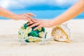 Male and female hands, two wedding rings with two starfish, wedding bouquet and a large shell on a sandy tropical beach. Blue sea Royalty Free Stock Photo