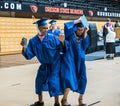 Male and female High school graduating seniors bump hips to celebrate diplomas