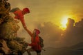 Male and female hikers climbing up mountain cliff and one of the Royalty Free Stock Photo