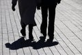 Couple walking down the street, silhouettes and shadows of two people on pedestrian sidewalk Royalty Free Stock Photo