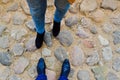 Male and female legs in leather shoes, boots on a stone road of large cobble stones opposite each other. The background Royalty Free Stock Photo