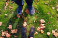 Male and female legs in sneakers and boots standing on ground with yellow autumn leaves Royalty Free Stock Photo