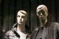 Male and female mannequins in a store window wearing dark clothes. Man and woman.